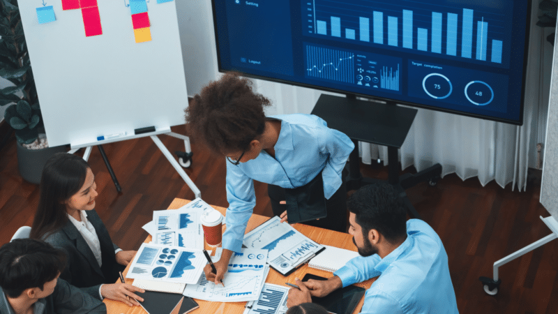 team of people looking at data on a screen and printouts